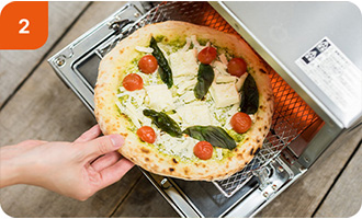 家庭用オーブントースターの網にピザをのせる様子