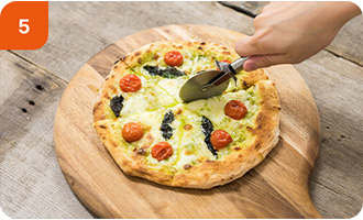 焼き上がったピザをカッターでカットしている様子